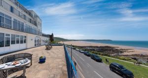ein Balkon mit neben einem Gebäude geparkten Autos und dem Meer in der Unterkunft Devon Beach Court, sea views of Woolacombe in Woolacombe