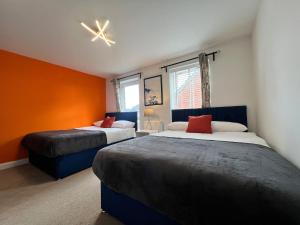 two beds in a room with orange walls at Spacious 5 Bed, Sleeps 12 with Parking, Contractors & Family Haven in Dartford