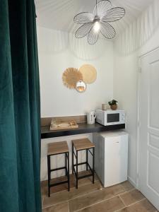 a kitchen with a counter with stools and a microwave at La chambre de Bodhi 