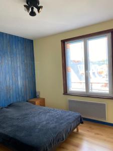 a bedroom with a bed and two large windows at Appartement meublé 52m2 in Bagnères-de-Bigorre