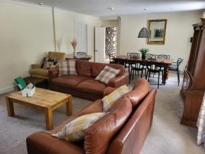 a living room with leather couches and a dining room at The Farmhouse, 6 bed property, Forres in Forres
