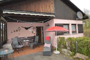 a pink house with a table and chairs and an umbrella at Haus Waldfrieden OG in Thalfang