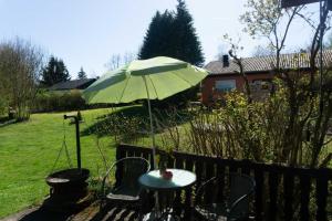 a table with a green umbrella in a yard at Haus Im Wiesengrund OG in Thalfang