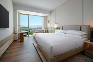 Courtyard by Marriott Korla في كورلا: غرفة نوم بها سرير أبيض كبير ونافذة كبيرة +42 صورة