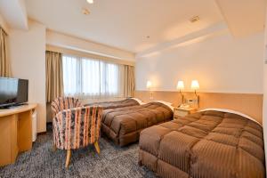 ein Hotelzimmer mit zwei Betten und einem Fernseher in der Unterkunft Hotel Sun Valley Annex in Beppu
