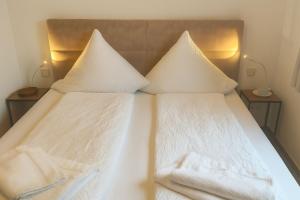 a bed with white sheets and pillows on it at Juister Zauber Ferienwohnung Sonnendüne in Juist +9 photos