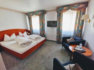 a hotel room with a bed and a chair at Kaiserstühler-Hof in Breisach am Rhein +25 photos