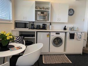 a kitchen with a washing machine and a microwave at Maison Blue - Chic Garden Apartment - Pet Friendly in Napier +25 photos