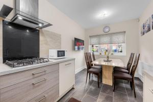 Una cocina con una mesa con sillas y una estufa. en 4 Bedroom House In Manchester, en Mánchester