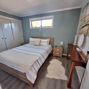 a bedroom with a bed and a desk and a window at Relax Break - Bazza's Shack in White Beach