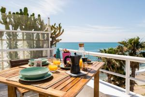 a table with food and drinks on a balcony overlooking the beach at Atico En Faro in Roquetas de Mar