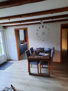 a dining room with a table and a clock on the wall at Appartement confortable avec terrasse in Zweisimmen