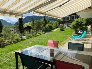 a patio with a table and chairs on a lawn at Appartement confortable avec terrasse in Zweisimmen