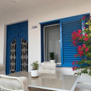 Habitación con puertas azules, mesa y sillas. en Un pequeño lujo a pocos metros de la playa, en Piles