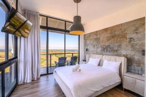 a bedroom with a white bed and a large window at לה כינרה - ווילה מדהימה עם בריכה פרטית מחוממת ונוף לכנרת במגדל in Migdal