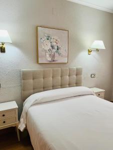 una camera con un letto bianco con due comodini e due lampade di Hotel Salvador a Bailén