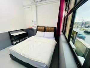 a bedroom with a bed in a room with a window at Singtown Guesthouse in Mersing