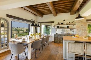 a dining room with a table and chairs and a kitchen at CASALE DEI GELSOMINI 8, Emma Villas in Todi