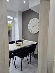 a dining room with a table and a clock on the wall at Long Short Stays Driveway 2-Bed Hull in Hull