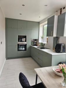a large kitchen with green cabinets and a table at Long Short Stays Driveway 2-Bed Hull in Hull