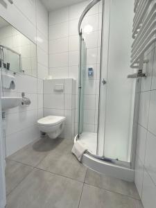 a bathroom with a shower and a toilet and a sink at Hotel Restauracja Kaukaska Jadwiga Choroszy in Wolsztyn