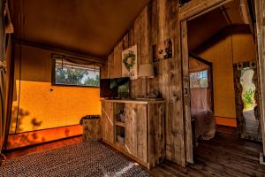 a room with a wooden wall with a door and a television at Glamping Tenuta Poggio Rosso in Populonia