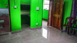 a green wall in a room with a table and chairs at Ziro Homestay in Hāpoli
