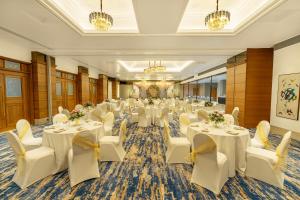 a banquet hall with white tables and white chairs at Hotel Kohinoor Continental, Airport in Mumbai
