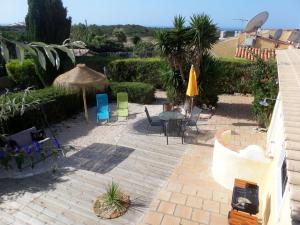 un patio con mesa, sillas y sombrilla en Nature Beach Resort Quinta Al-Gharb en Vila do Bispo