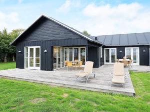 a black house with a wooden deck and chairs at 5 star holiday home in Nysted in Nysted