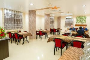 a restaurant with tables and chairs and people sitting at tables at Hotel Avon International in Aurangabad