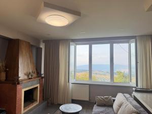 a living room with a fireplace and a large window at apartment in Kojori in Tbilisi City