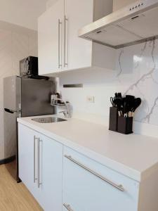 a white kitchen with a sink and a refrigerator at Stunning 42nd Floor Apt with Netflix in Manila