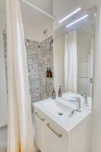 a white bathroom with a sink and a shower at Appartement agréable Parking inclus in Aubervilliers