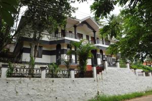 a large white house with a stone wall at Palm View Residency in Varkala