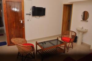 a room with two chairs and a table and a tv at Palm View Residency in Varkala