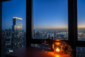 a window with two glasses of wine and candles at Luxe 3BR Skyline Sunset Residence Level 63 - CBD Views, Parking, Pool, Sauna, Gym in Melbourne