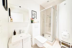 a white bathroom with a toilet and a shower at Appartement Spacieux 80 m2 in Bobigny