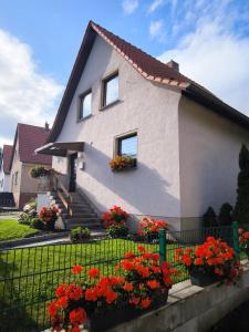 a house with flowers in front of a fence at Ferienhaus Isabel mit Pool und Garten Nähe Quedlinburg in Gernrode - Harz