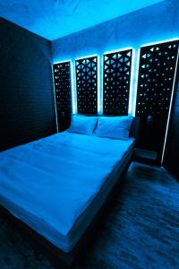 Bett in einem Zimmer mit blauem Licht in der Unterkunft The Industry in Galaţi