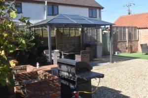 a barbecue grill with a blue canopy in a yard at Swallow cottage in Louth
