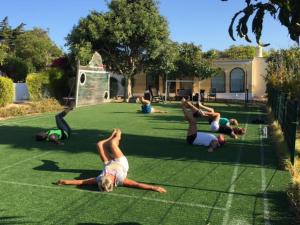 een groep mensen die yoga doen op het gras bij Nature Beach Resort Quinta Al-Gharb in Vila do Bispo