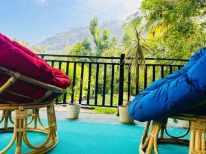 Dos sillas sentadas en un porche con vista. en Ambuluwawa View Inn, en Gampola