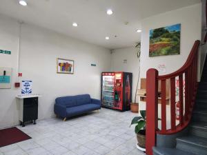 a room with a blue couch and a soda machine at Oceanic Hostel in Auckland