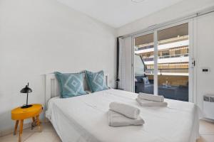 a bedroom with a large white bed with blue pillows at PALACIO- Centre-Ville - Parking privé - Proche Mer - Grande terrasse in Menton