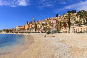 people laying on the beach in front of a city at PALACIO- Centre-Ville - Parking privé - Proche Mer - Grande terrasse in Menton
