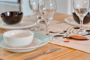 a wooden table with plates and wine glasses on it at Appartement Spacieux 80 m2 in Bobigny