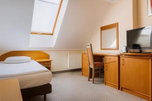 a bedroom with a bed and a desk and a tv at Hotel Victory Home - 10min Lotnisko Chopina, 15min to Zachodni, 5min to Progresja in Warsaw +60 photos