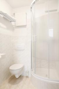 a white bathroom with a toilet and a shower at Hotel Victory Home in Warsaw