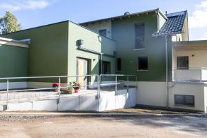 a green and white building with a balcony at Ferienwohnungen im Waldhaus Sebnitz in Sebnitz